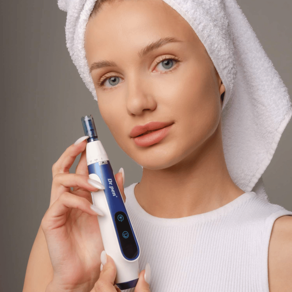 Femme avec une serviette autour des cheveux tenant un stylo Dr. Pen A11 microneedling – appareil de soin de la peau professionnel pour une peau plus lisse et plus ferme.